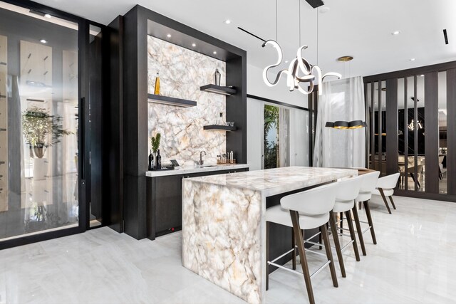 kitchen featuring light stone counters, pendant lighting, expansive windows, a chandelier, and a center island