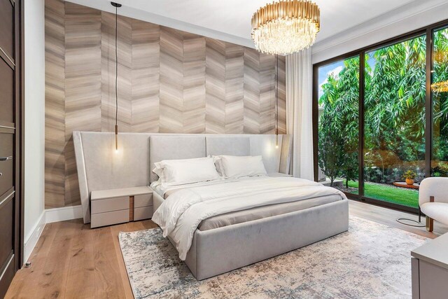 bedroom featuring access to outside, light wood-type flooring, and a chandelier