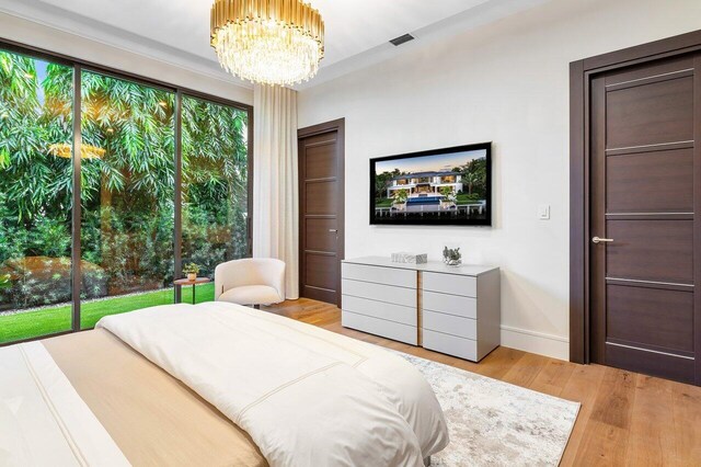 bedroom with light hardwood / wood-style flooring, access to exterior, and an inviting chandelier