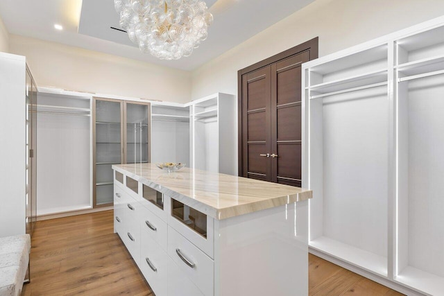 walk in closet with light hardwood / wood-style flooring and a chandelier