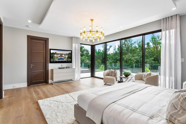 bedroom with an inviting chandelier, light wood-type flooring, and access to exterior