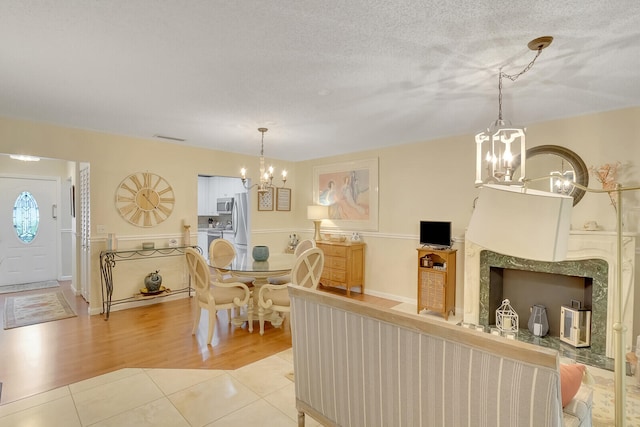 living room featuring light wood-type flooring, a textured ceiling, and a chandelier