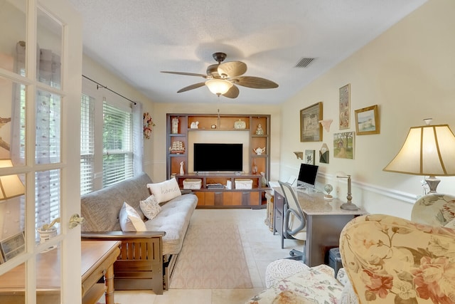 living room with a textured ceiling, light tile patterned floors, and ceiling fan