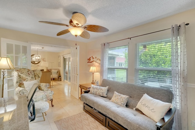 living room featuring ceiling fan with notable chandelier, a textured ceiling, and light tile patterned floors