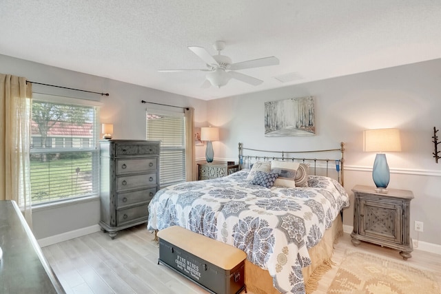 bedroom featuring ceiling fan, a textured ceiling, and light hardwood / wood-style floors