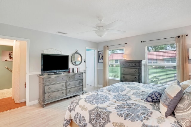 bedroom with light hardwood / wood-style floors, ceiling fan, and a textured ceiling