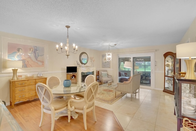 dining space featuring an inviting chandelier, light wood-type flooring, and a textured ceiling