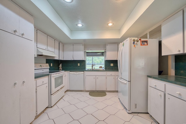 kitchen featuring backsplash, white appliances, a raised ceiling, sink, and white cabinetry