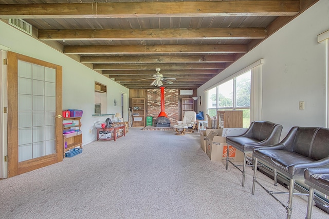 playroom featuring carpet, a wood stove, ceiling fan, and beamed ceiling