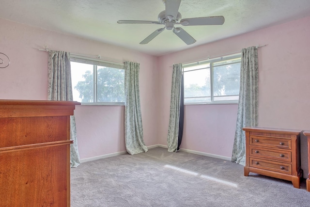 unfurnished bedroom featuring multiple windows, light carpet, and ceiling fan