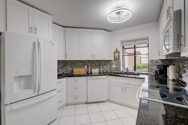 kitchen with white appliances, dark stone countertops, and white cabinets