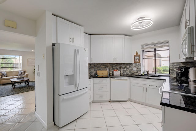 kitchen featuring tasteful backsplash, white cabinetry, sink, light tile patterned floors, and white appliances