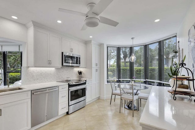 kitchen featuring tasteful backsplash, white cabinetry, appliances with stainless steel finishes, decorative light fixtures, and ceiling fan