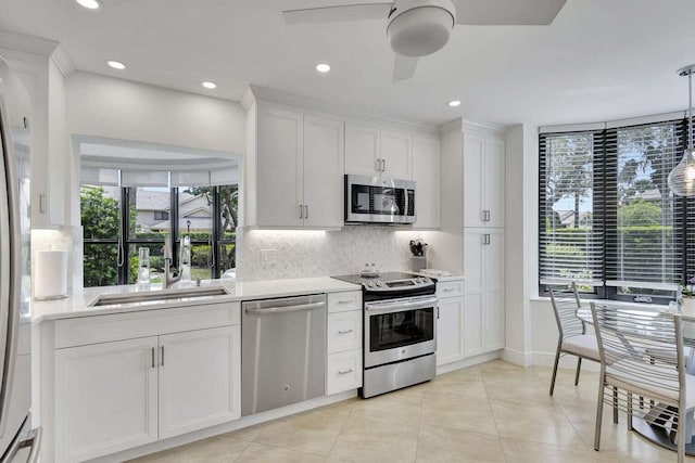 kitchen with stainless steel appliances, white cabinets, ceiling fan, and hanging light fixtures