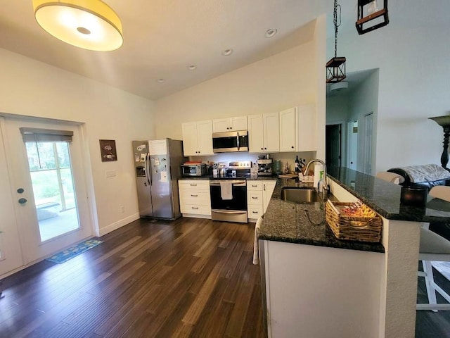 kitchen with lofted ceiling, kitchen peninsula, white cabinetry, sink, and stainless steel appliances