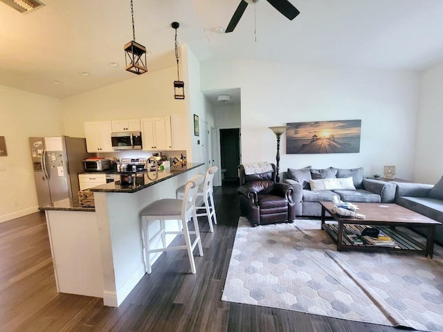 kitchen with white cabinets, open floor plan, hanging light fixtures, a peninsula, and stainless steel appliances