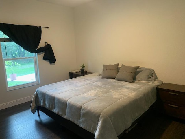 bedroom with baseboards and dark wood-type flooring