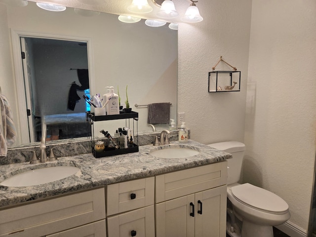 full bathroom with double vanity, a sink, toilet, and ensuite bathroom