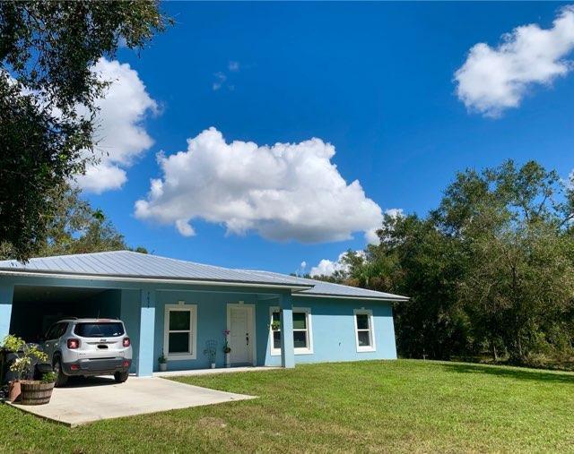 single story home featuring concrete driveway, a front lawn, a carport, and stucco siding