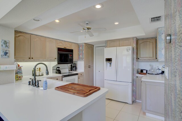 kitchen featuring ceiling fan, light brown cabinets, sink, white appliances, and a tray ceiling