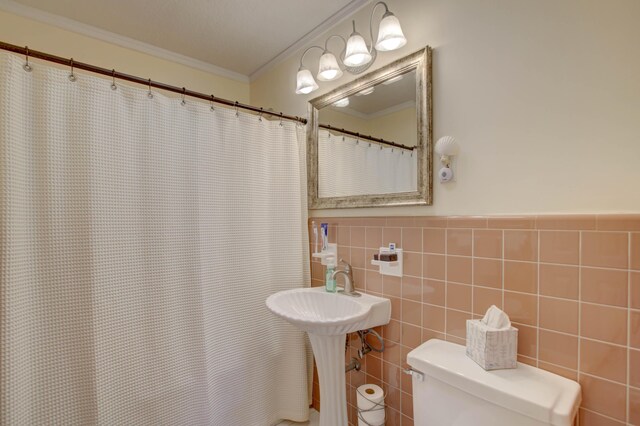 bathroom featuring crown molding, tile walls, and toilet