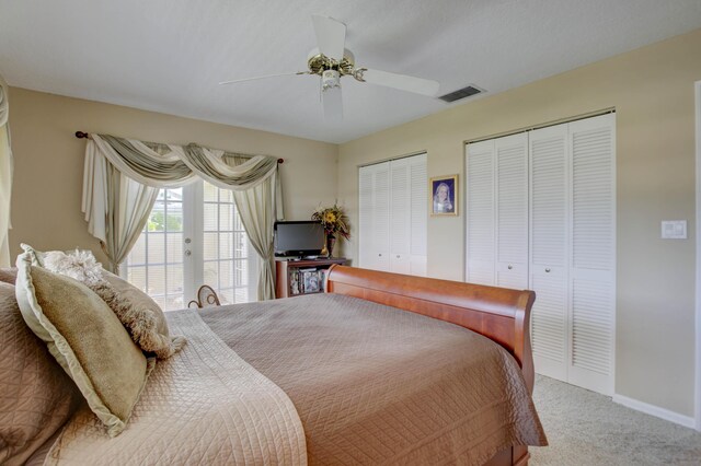 carpeted bedroom featuring ceiling fan and two closets