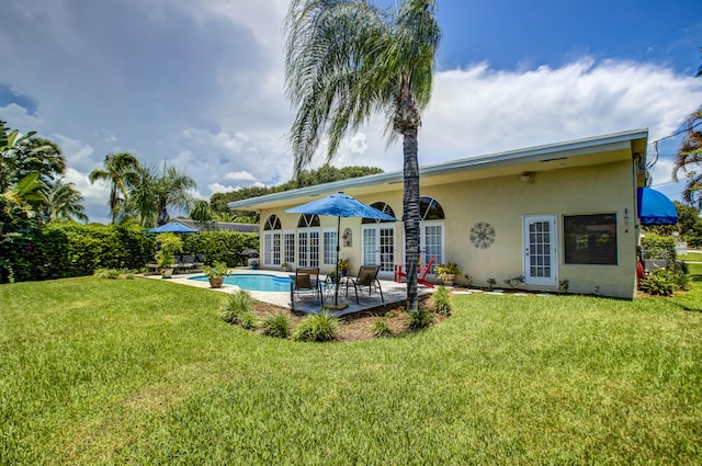 rear view of property featuring a patio, a fenced in pool, and a lawn