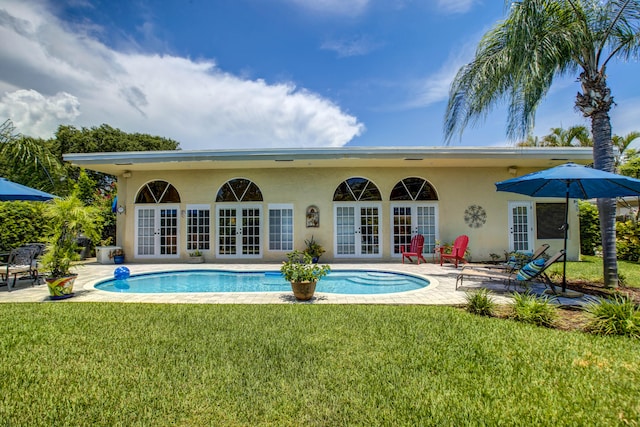 rear view of house featuring a lawn, french doors, and a patio