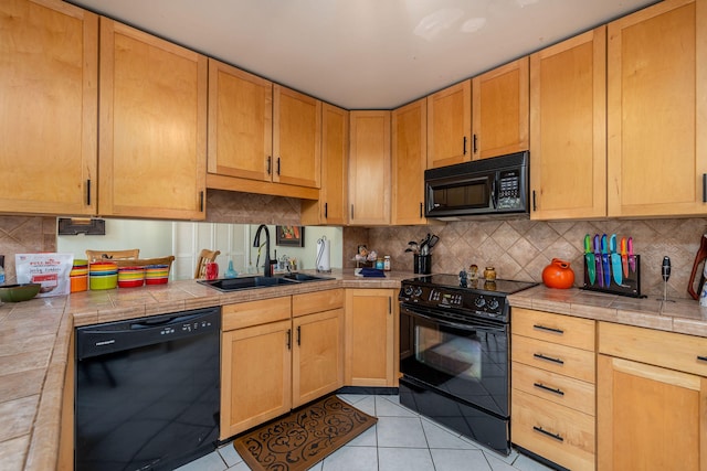 kitchen with black appliances, sink, light tile patterned floors, and tile countertops