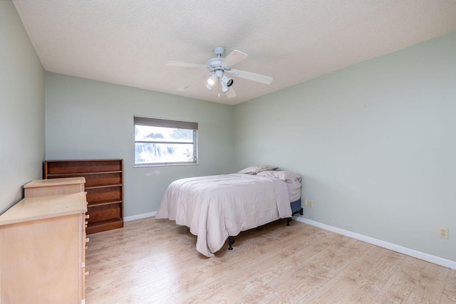 bedroom with light wood-type flooring, a textured ceiling, and ceiling fan