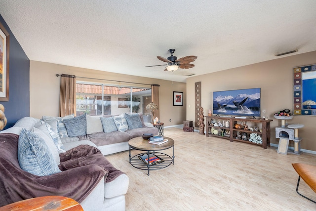 living room with ceiling fan, a textured ceiling, and light hardwood / wood-style flooring