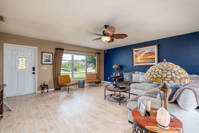 living room featuring light wood-type flooring, ceiling fan, and a textured ceiling