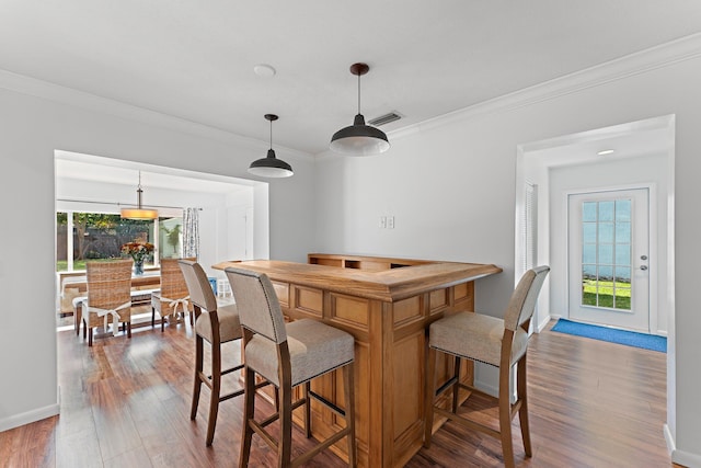 kitchen with dark wood-type flooring, decorative light fixtures, and crown molding