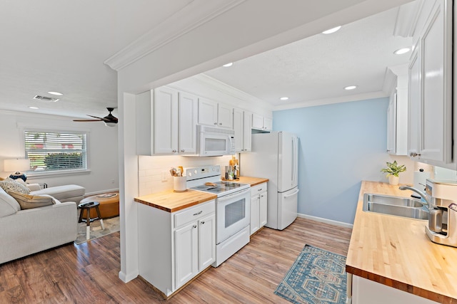 kitchen with butcher block countertops, white cabinetry, white appliances, and sink