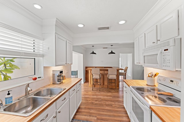 kitchen with butcher block counters, white appliances, white cabinetry, and sink