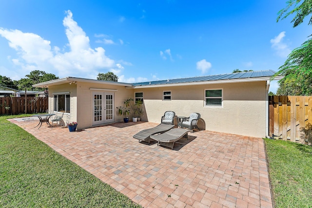 back of property with a patio, a lawn, and french doors