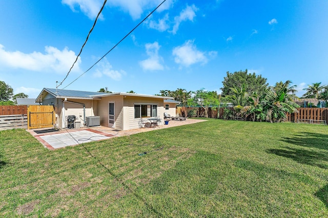 rear view of house with a lawn, central AC, and a patio area