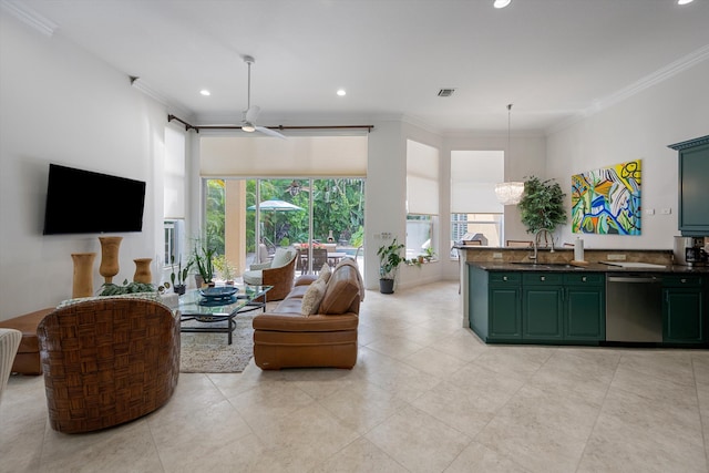 living room with ceiling fan with notable chandelier, ornamental molding, and sink