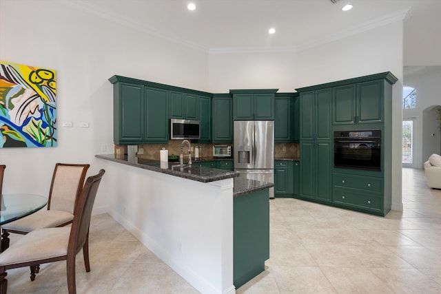 kitchen featuring dark stone counters, green cabinets, stainless steel appliances, kitchen peninsula, and ornamental molding