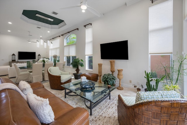 living room with a raised ceiling, crown molding, and ceiling fan