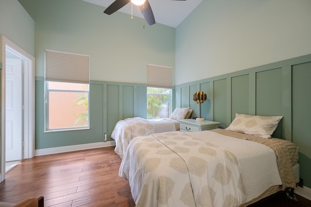 bedroom with wood-type flooring, multiple closets, high vaulted ceiling, and ceiling fan