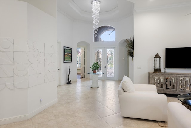 living room featuring an inviting chandelier, a towering ceiling, ornamental molding, and light tile patterned flooring