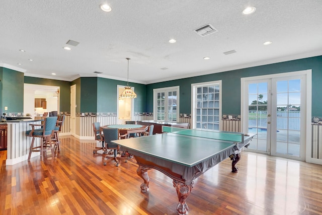 dining space with ornamental molding, a textured ceiling, and hardwood / wood-style flooring