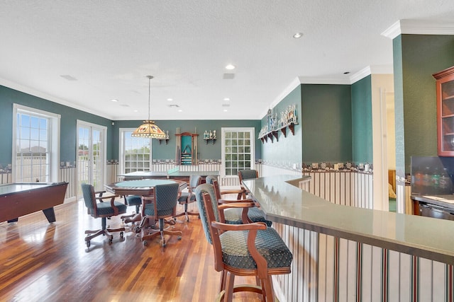 dining area featuring wood-type flooring, ornamental molding, a textured ceiling, and pool table