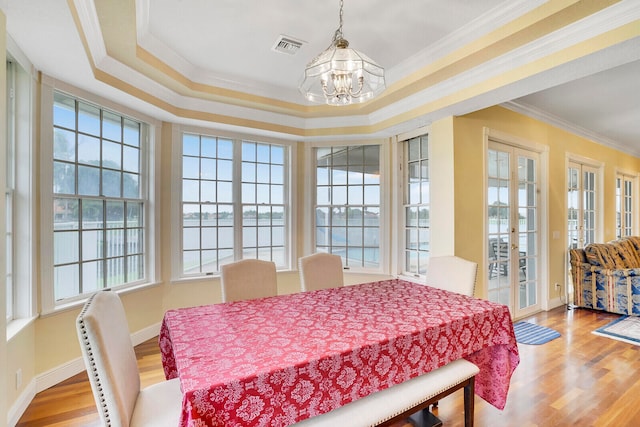 dining area with light hardwood / wood-style flooring, a chandelier, a tray ceiling, and crown molding