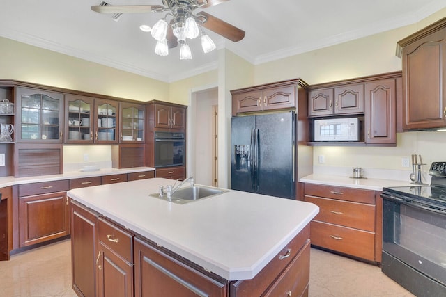 kitchen featuring ceiling fan, an island with sink, sink, black appliances, and crown molding