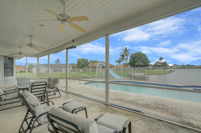 sunroom featuring ceiling fan and a pool