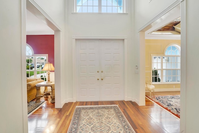 dining area featuring a towering ceiling, ornamental molding, hardwood / wood-style floors, and a chandelier