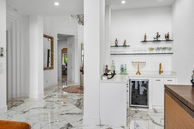 bar with white cabinets, wine cooler, and sink