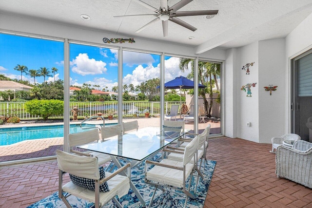 sunroom with a water view and ceiling fan